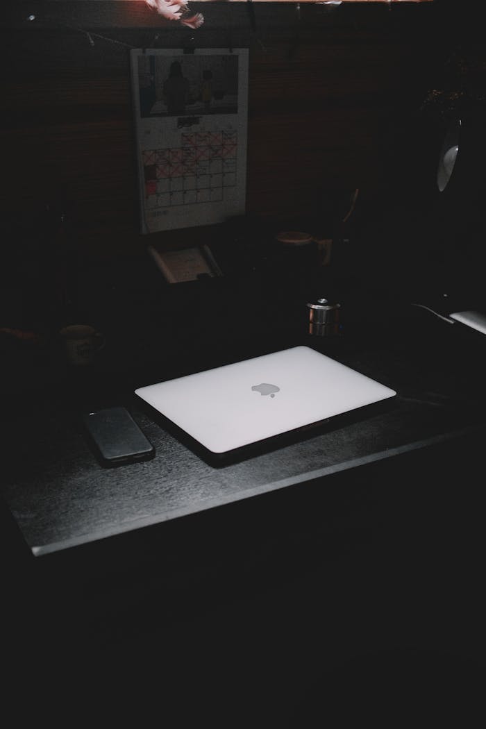 about-us A dark, minimalist workspace featuring a laptop and smartphone on a desk.