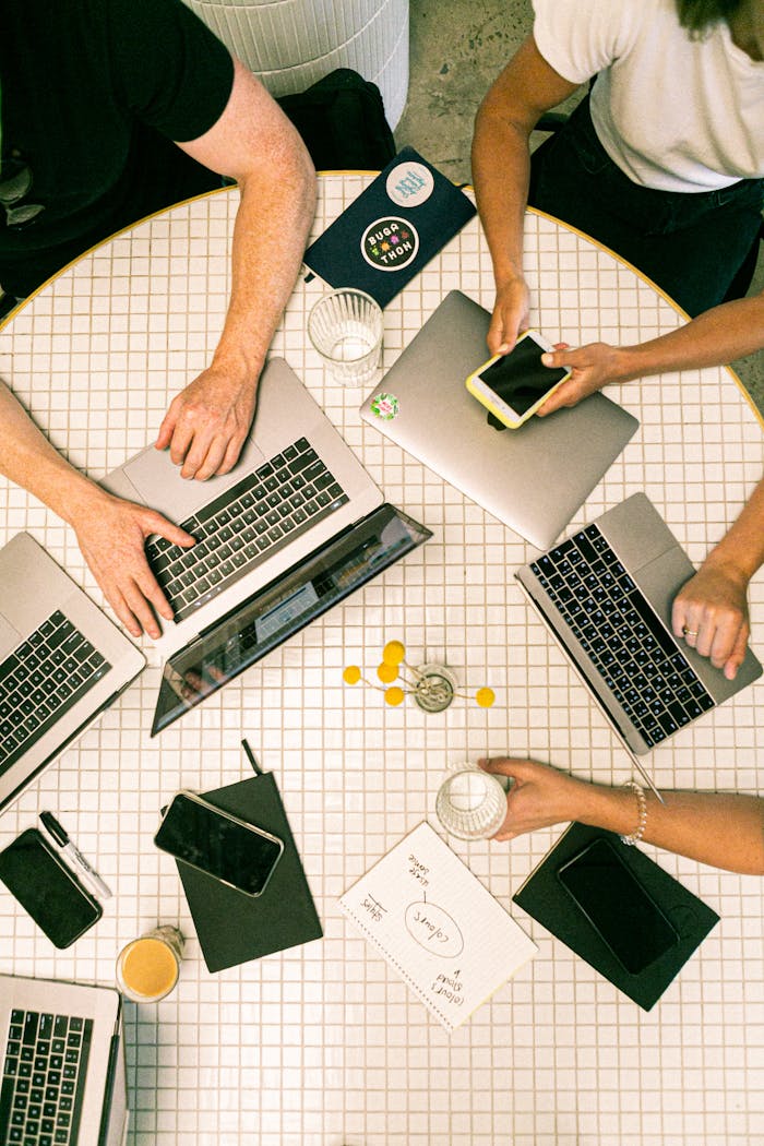 services-02 Top view of a team collaborating with laptops, phones, and notes in a modern office.